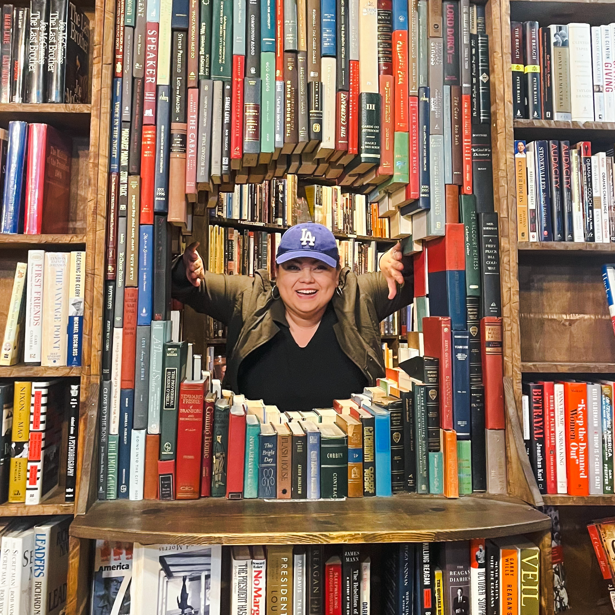Sam Arias digital content creator smiling inside a book tunnel at a library, representing creativity and storytelling.
